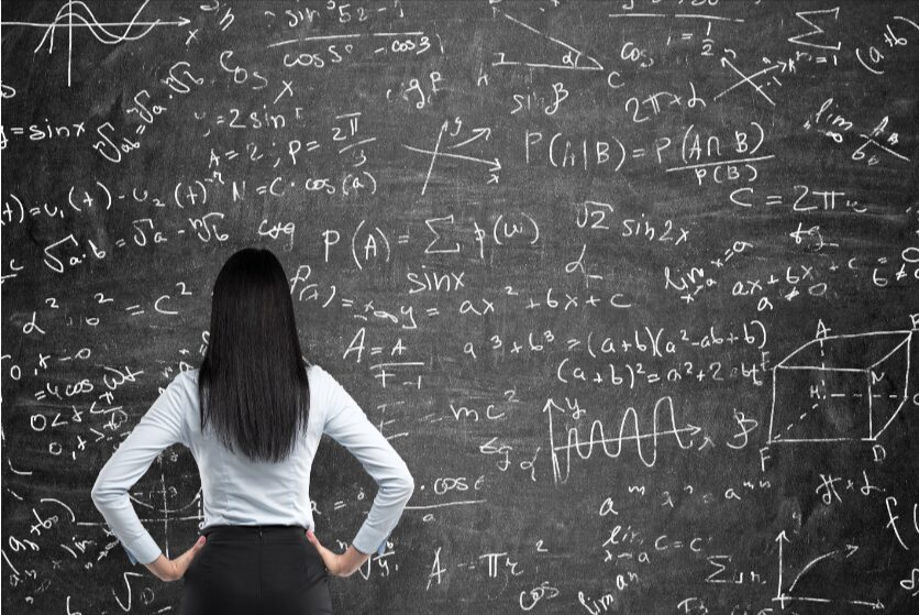 Woman standing in front of a chalkboard filled with math equations