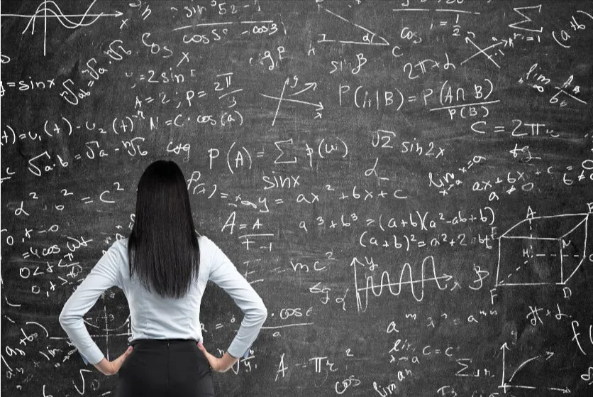 Woman standing in front of a chalkboard filled with math equations